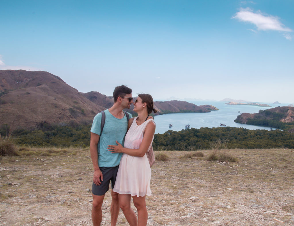 2 people standing close to each other in front of a bay with many hills whilst on a Komodo tour