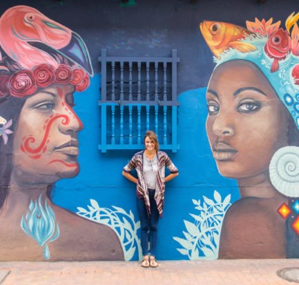 a pretty girl posing in front of a mural displaying two women in Bogota, Colombia