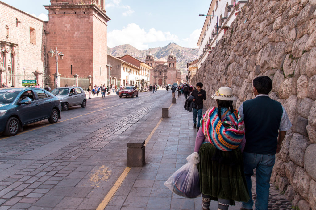 a street with pedestrians and cars in Cusco, Peru