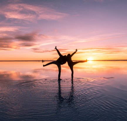 two people posing on salt flats during sunset colours and water reflection in Bolivia
