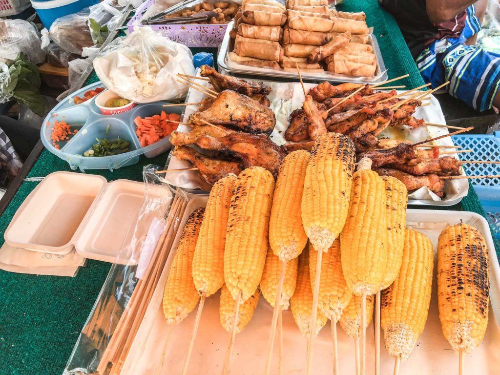 corn, chicken and spring rolls displayed during lunch time on a beach in Krabi region