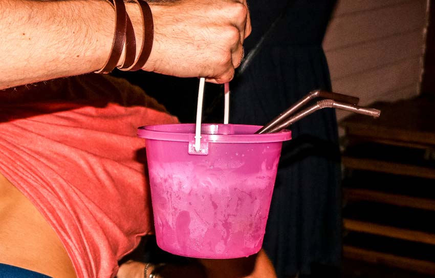 a person holding a pink bucket with two straws