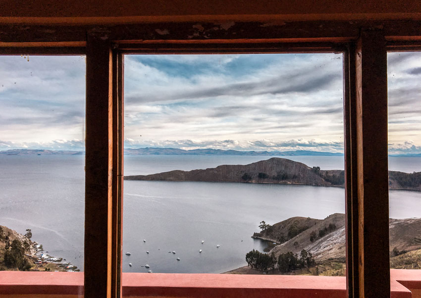 View out of a hotel window on  lake titicaca and a mountain range in the distance