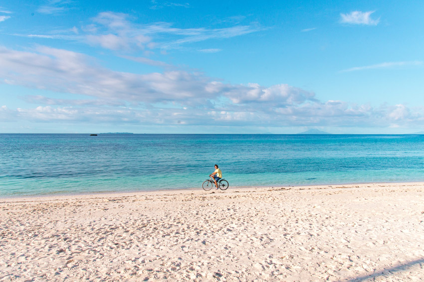a boy riding a bicycle on the white sand beach