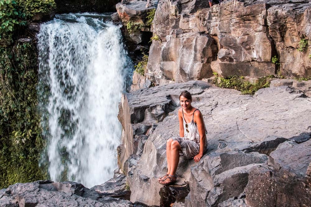Girl sitting in front of a waterfall.