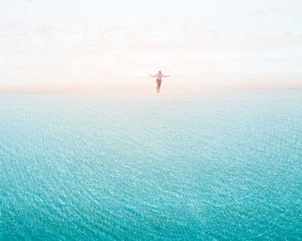 aerial view on a girl lying on a beach in front of blue water in the Philippines