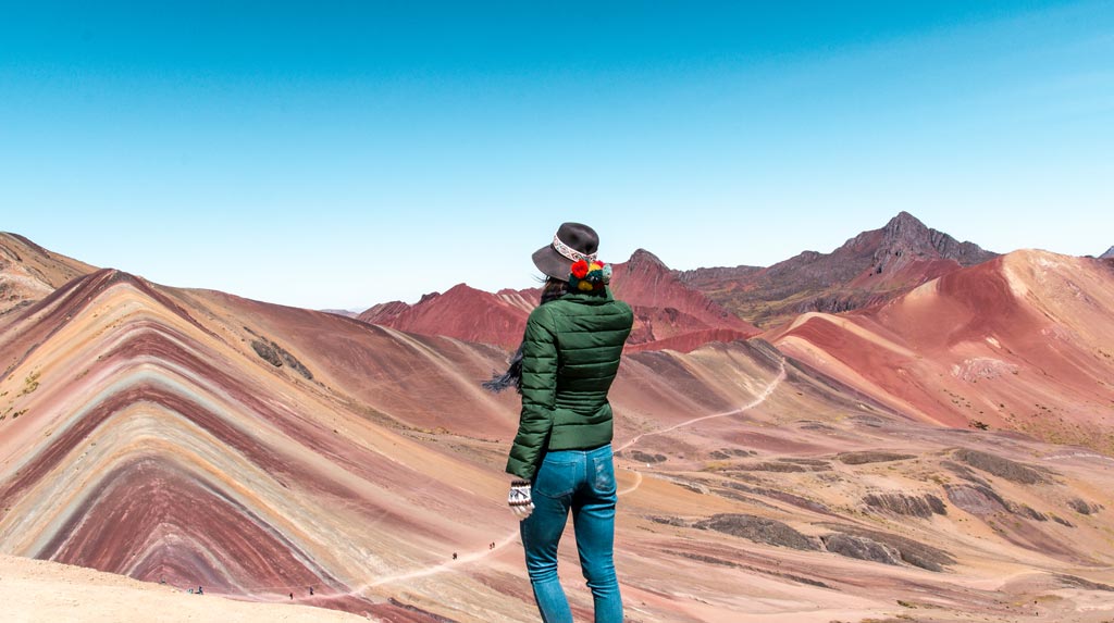 A girl enjoys the view on Vinicunca Rainbow Mountain Peru