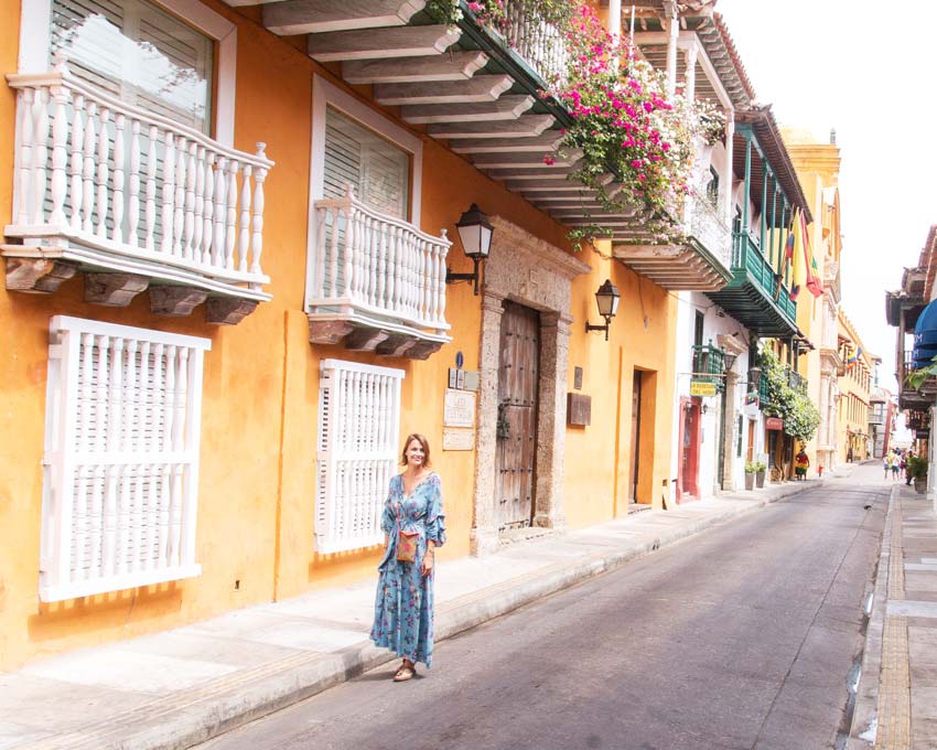 woman in front of colorful street of Cartagena which has to be in your 2 weeks itinerary when exploring Colombia