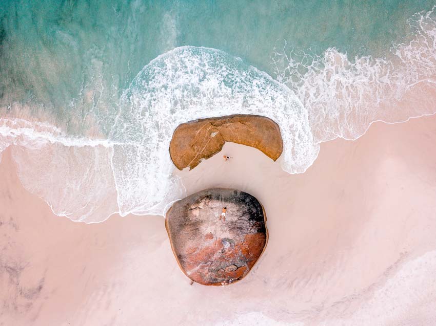 2 rocks on a beach surrounded by water