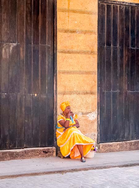 cuban lady in a yellow dress smoking a cigar in Havana