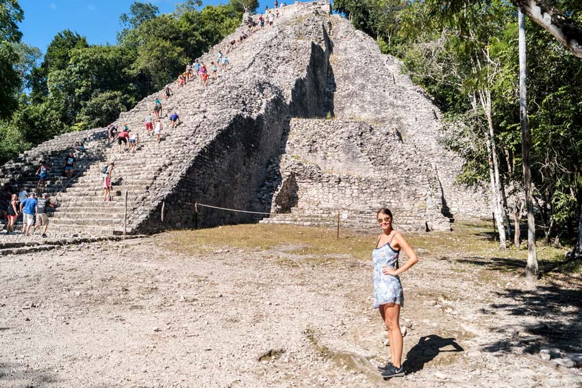 a woman standing in front of the pyramid in Coba