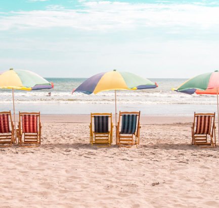 three beach umbrellas and six beach chairs on the beach in Montanita, Ecuador
