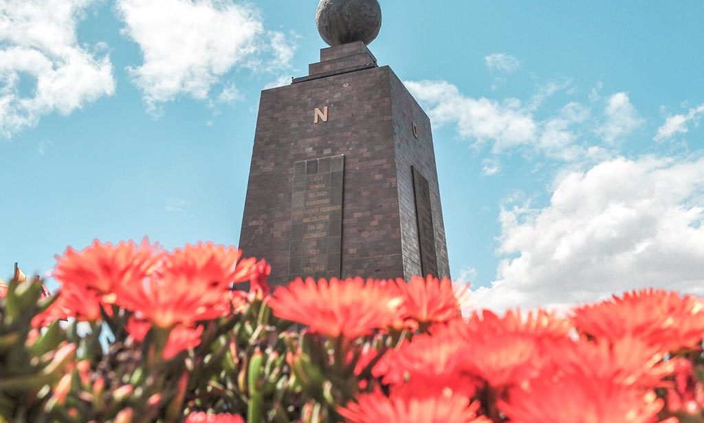 red flowers and grey monument at Mitad Del Mundo, Ecuador