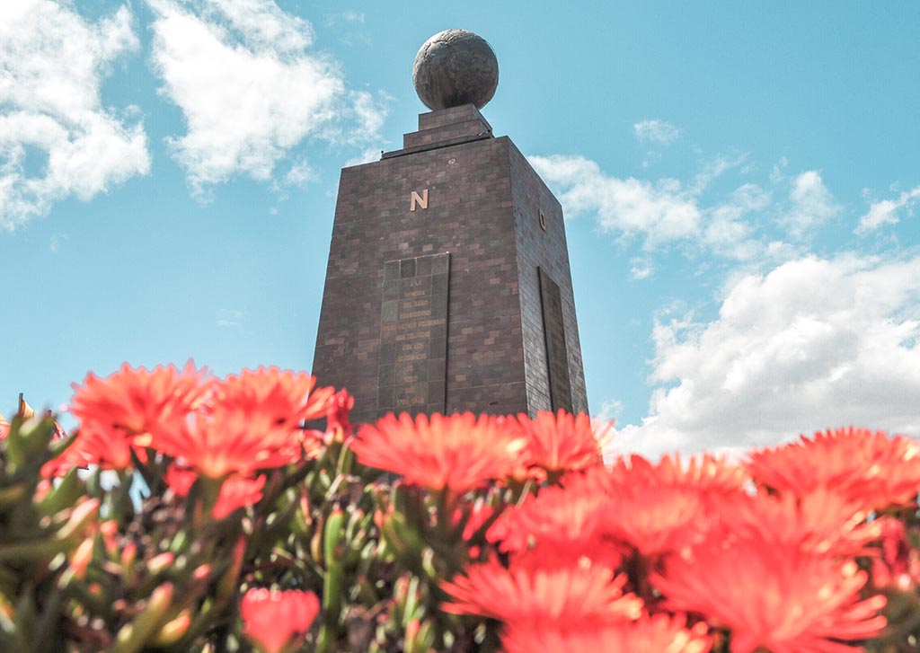 red flowers and grey monument at Mitad Del Mundo, Ecuador
