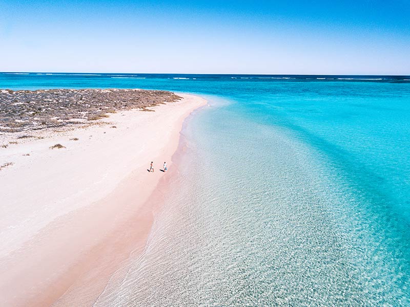 aerial shot of the blue sea, white sand and two people walking in Cape Range National park