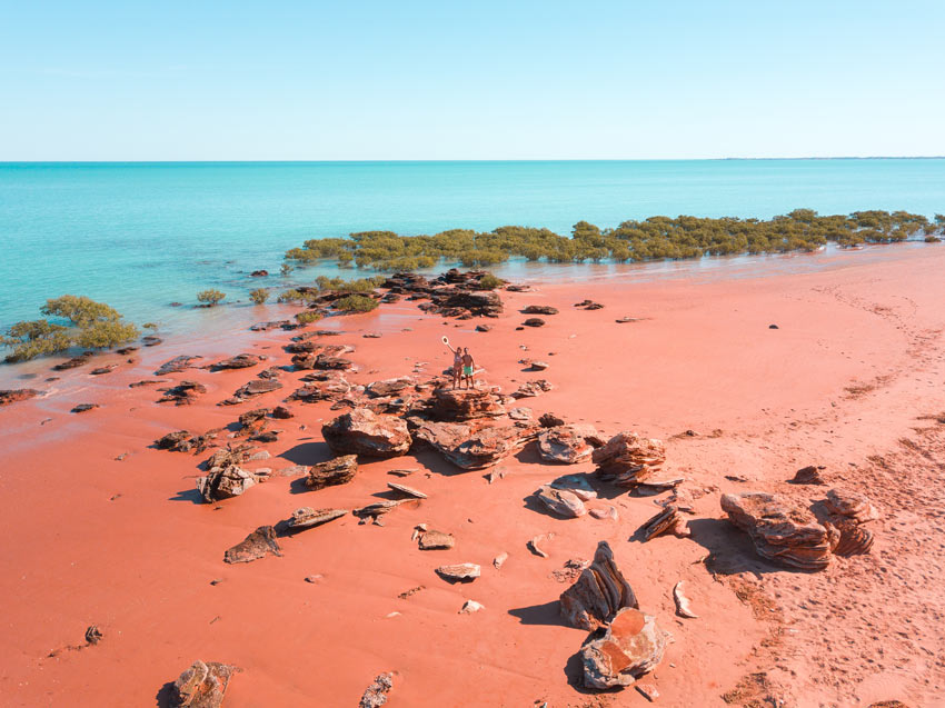 drone shot with red beach, two people blue water and green mangroves near Broome, Western Australia